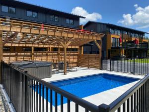 una piscina con pérgola de madera y un edificio en Le Memph Aigle spacious comfortable condo cottage eco friendly 3 bedrooms - hot tub & pool Memphrémagog Lake, en Magog-Orford