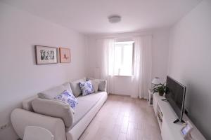een witte woonkamer met een bank en een televisie bij Modern apartment Grbin in the very center of Korcula in Korčula