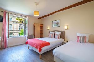 two beds in a room with a window at Hotel Val De Loire in Azay-le-Rideau