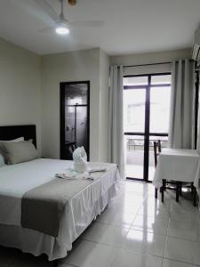 Hotel Albinos في إيتابيرونا: غرفة نوم بسرير وكرسي ونافذة