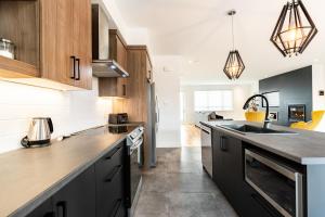 una cocina con armarios en blanco y negro y electrodomésticos de acero inoxidable en Le Memph Aigle spacious comfortable condo cottage eco friendly 3 bedrooms - hot tub & pool Memphrémagog Lake en Magog-Orford