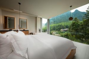 a bedroom with a white bed and a large window at ANNICA Villa in Zhangjiajie