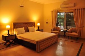 a bedroom with a bed and two chairs and a window at Reina Boutique Hotel - G6 in Islamabad