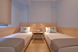 two beds in a room with a table between them at Niel Holiday Apartments, Panel Hospitality Homes & Villas in Leptokaria