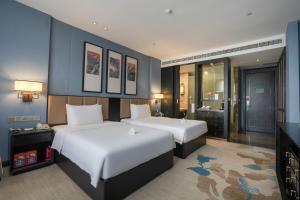 Chongqing Hilman Homeful Hotel في تشونغتشينغ: غرفة نوم بسريرين وجدار ازرق