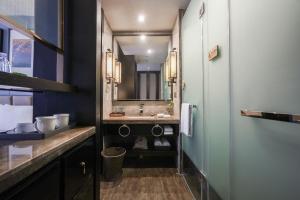 W łazience znajduje się umywalka i lustro. w obiekcie Chongqing Hilman Homeful Hotel w mieście Chongqing