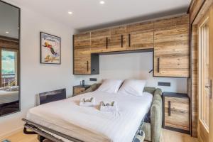 una camera da letto con un grande letto bianco e armadi in legno di Studio Belvédère - Welkeys a Megève