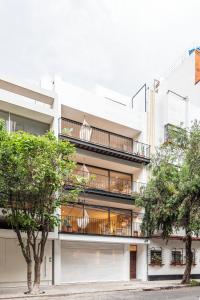 un edificio de apartamentos con balcones y árboles en Casa Antonio by Kukun, en Ciudad de México