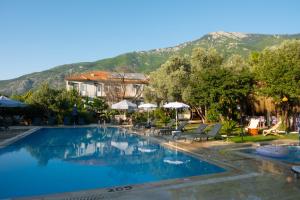 a hotel with a swimming pool with mountains in the background at Kibele Hotel in Oludeniz