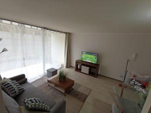 a living room with a couch and a tv at Departamento Avda Pacifico La Serena in La Serena