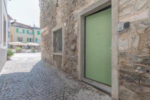 ein Steingebäude mit grüner Tür auf einer Straße in der Unterkunft La Piazzetta in Iseo
