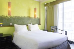 uma grande cama branca num quarto com uma mesa em Hotel Fundador em Santiago