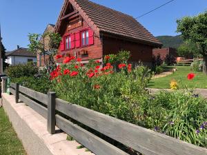 une clôture en bois devant une maison fleurie dans l'établissement Chalet Colline et Lou, à Wintzfelden