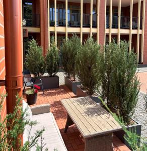 a patio with a table and potted plants in front of a building at Rusnės Perlo apartamentai in Rusnė