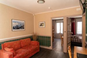 sala de estar con sofá rojo y mesa en Hôtel Le Pas de L'Ours, en Cauterets