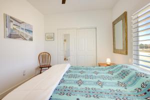 a white bedroom with a bed and a chair at Serene Pahrump Cottage with Mountain Views! in Pahrump