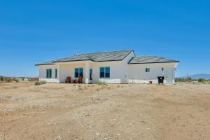 a white house in the middle of a dirt field at Serene Pahrump Cottage with Mountain Views! in Pahrump