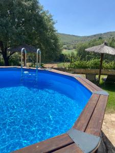 una piscina azul con banco y sombrilla en El Balcón De Alboreca en Alboreca