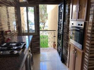 a kitchen with a stove and a door to a balcony at 100m² avec parking gratuit proche de la plage in Mohammedia