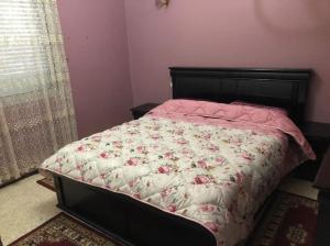 a bedroom with a bed with a bedspread with roses at 100m² avec parking gratuit proche de la plage in Mohammedia