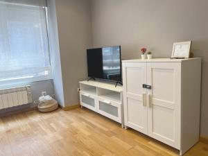 - un salon avec une télévision et une armoire blanche dans l'établissement Gijón Playa by FlowHome, à Gijón