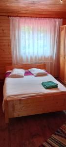 a bed in a wooden room with a window at La Malul Arieșului in Gîrda de Sus