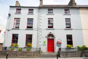 a white house with a red door at Kilkenny Tourist Hostel in Kilkenny