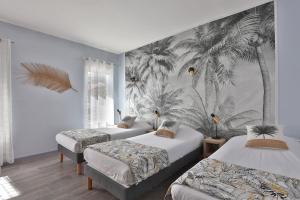 een slaapkamer met 2 bedden en een muurschildering van palmbomen bij Hotel du Cap in Capbreton
