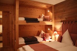 1 Schlafzimmer mit 3 Betten in einem Holzzimmer in der Unterkunft Chalet Tannenhof in Lermoos