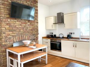 una cocina con armarios blancos y una pared de ladrillo en Central Location 2 bed flat, Zone II, London NW6 en Londres