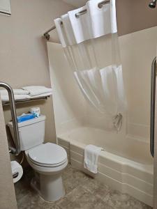 a bathroom with a toilet and a bathtub with a shower curtain at Crookston Inn & Convention Center in Crookston