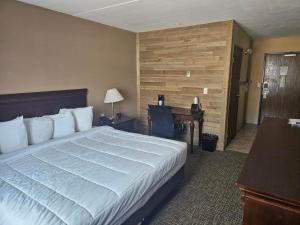 ein Hotelzimmer mit einem großen Bett und einem Schreibtisch in der Unterkunft Crookston Inn & Convention Center in Crookston