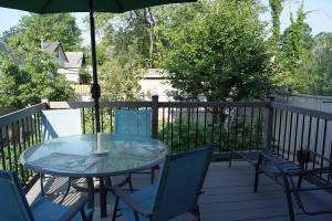 una mesa y sillas en una terraza con sombrilla en Pelican guest house. Village style living. Spend vacation time in Eco place! en Fort Erie