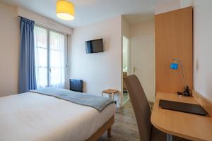 ein Schlafzimmer mit einem Schreibtisch, einem Bett, einem Schreibtisch und einem Computer in der Unterkunft Hotel Val De Loire in Azay-le-Rideau