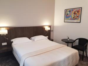 una habitación de hotel con una gran cama blanca y una silla en HOTEL ALISON en París