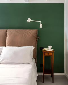 een bed met een groene muur en een tafel met een lamp bij Savadè Cefalù in Cefalù