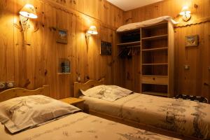 2 camas en una habitación con paredes de madera en Hôtel Le Pas de L'Ours en Cauterets