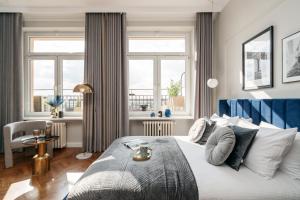 a bedroom with a bed with a blue headboard and windows at Penthouse Panorama - LoftAffair in Kraków +114 photos