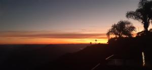 una puesta de sol con palmeras en una colina en Recanto Ninho das Aguias, en Nova Petrópolis