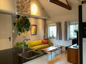 uma cozinha e sala de estar com um sofá amarelo em B&B Het Postkantoortje em Gorssel