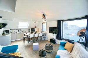 een woonkamer met een blauwe bank en een keuken bij L’Effet Mer*70m de la mer*Prise voiture électrique in Ploemeur