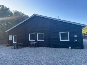 um edifício preto com uma mesa e cadeiras em frente em B&B Stald Saga em Herning