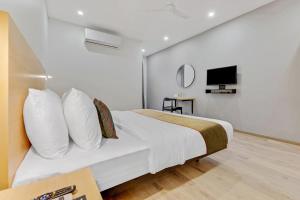 een slaapkamer met een bed met witte kussens en een televisie bij Townhouse Sector Near Logix city centre in Noida