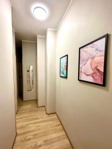 Un pasillo con dos cuadros en la pared y un pasillo con una puerta cerrada. en MMRent Sparrow Room, en Gdansk