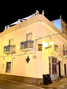 un edificio blanco con balcones en una calle por la noche en Casa Castelar by Bossh Apartments, en Rota