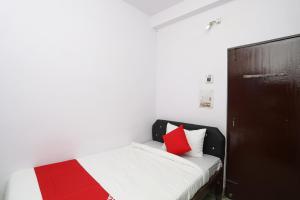 a bedroom with a bed with red and white pillows at Collection O Aditya Inn in Jamshedpur