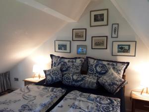 Schlafzimmer mit einem Bett mit blauen und weißen Kissen in der Unterkunft Das Rosenhaus in Utersum