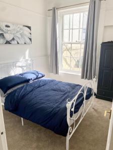 1 dormitorio con cama con sábanas azules y ventana en 2 bed flat, 1 bed flat Torquay, Torbay, Devon, en Torquay