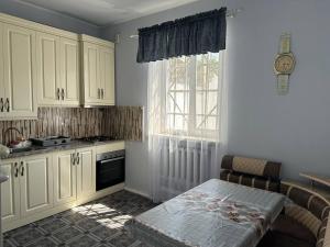 cocina con armarios blancos, fogones y ventana en Your Getaway Home, en Ereván