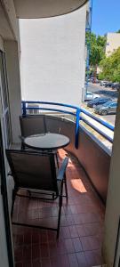 d'une table et d'une chaise sur un balcon offrant une vue sur la rue. dans l'établissement Aconchegante T3 em Telheiras, à Lisbonne
